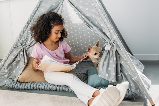 young girl reading in a home made fort