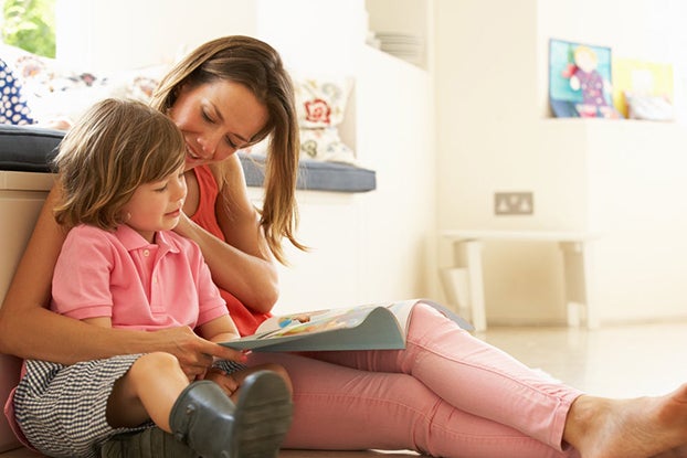 Mom helping young daughter with her reading