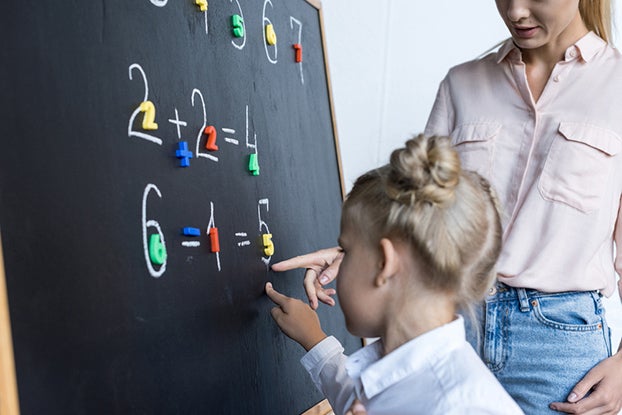 Child and teacher doing math on a chalkboard