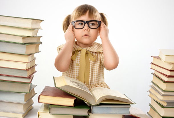 cute girl wearing glasses next to a stack of books