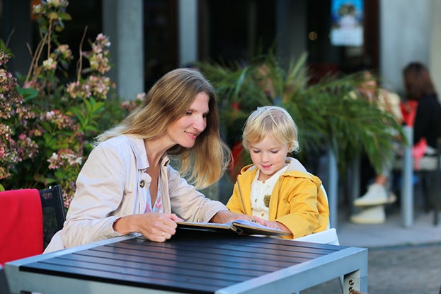 Mom reading to child at a table to teach print awareness