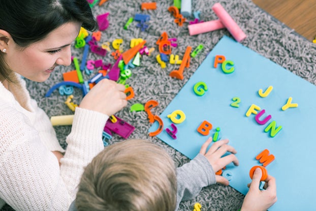 Mom and son playing with plastic letters to learn segmenting words