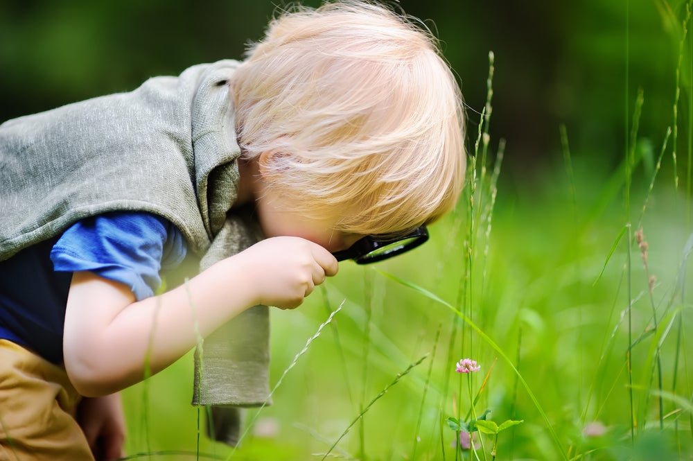 Kid exploring nature with magnifying glass
