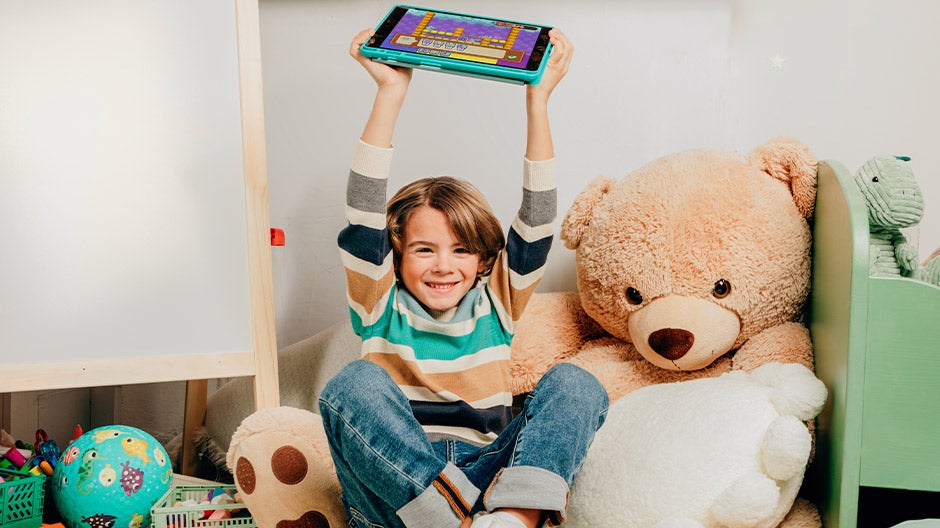 Child holding tablet above head in excitement
