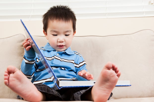 young kid looking at book working emergent literacy