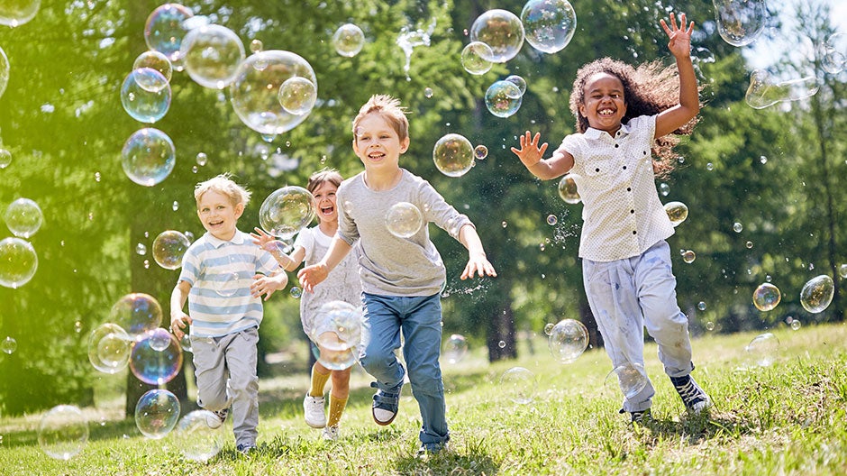 Kids playing with bubbles outside in a park