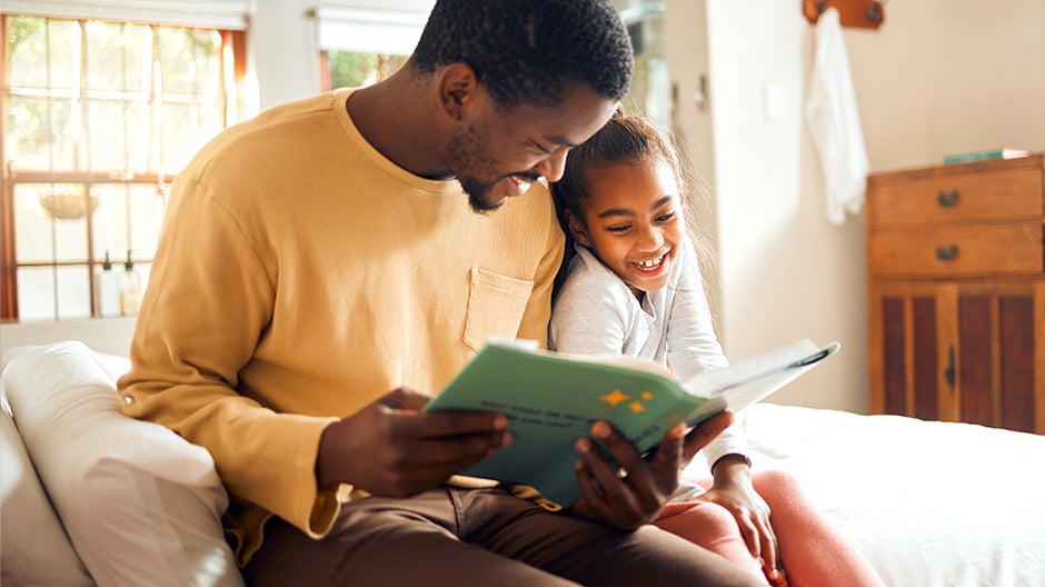 Father reading book about emotional self-regulation with daughter