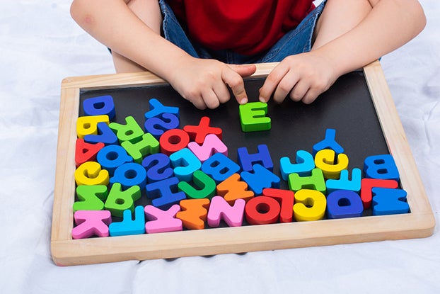 kid learning phonics with block letters