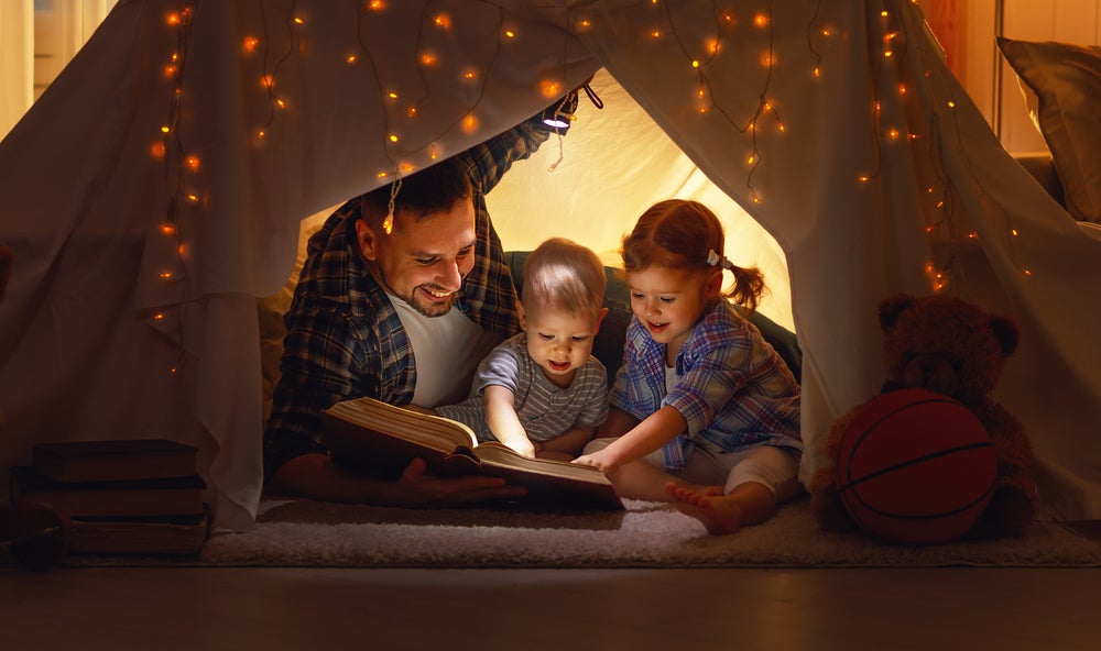 Dad reading to kids in a tent to show them calming strategies for kids