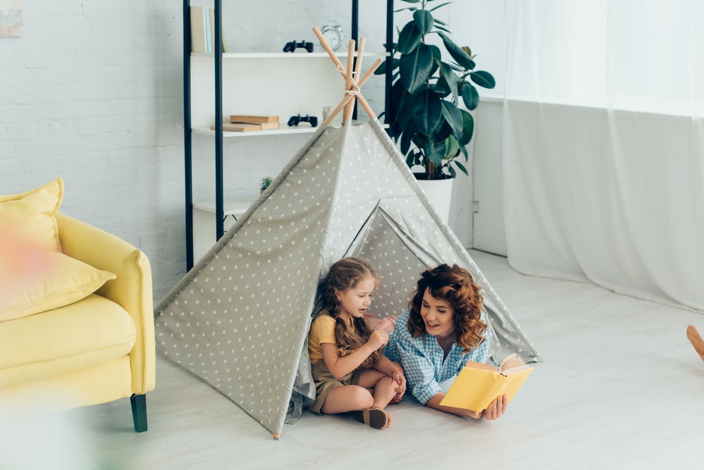 Mom reading with daughter in a fort