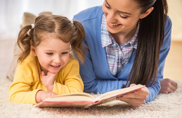 Young mother is reading a book to her cute daughter.