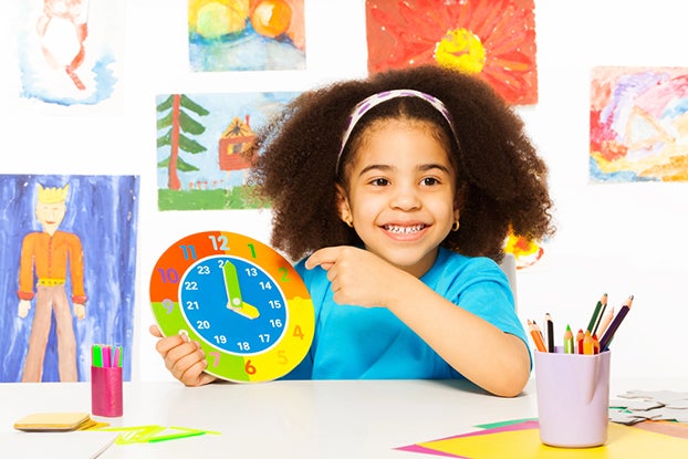 Kid leaning to tell time using a paper clock