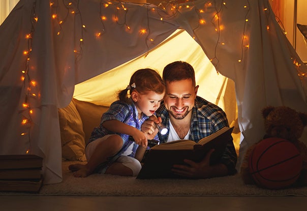 dad reading aloud to child in tent